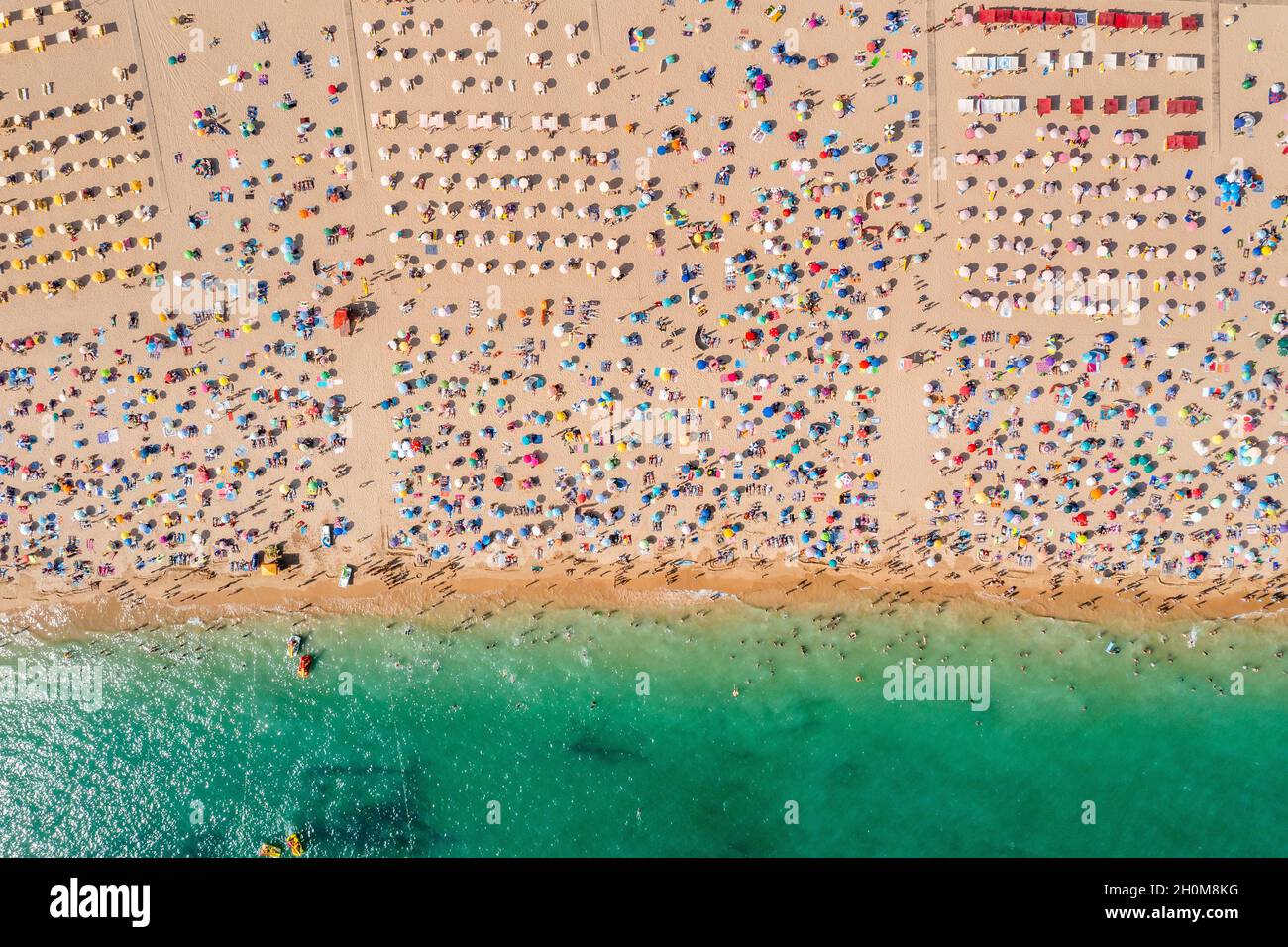 Drohnenaufnahme von vielen Menschen, die den Strand und das Meer genießen - Urlaubsmuster. Rocha Beach in Portimao, Portugal Stockfoto