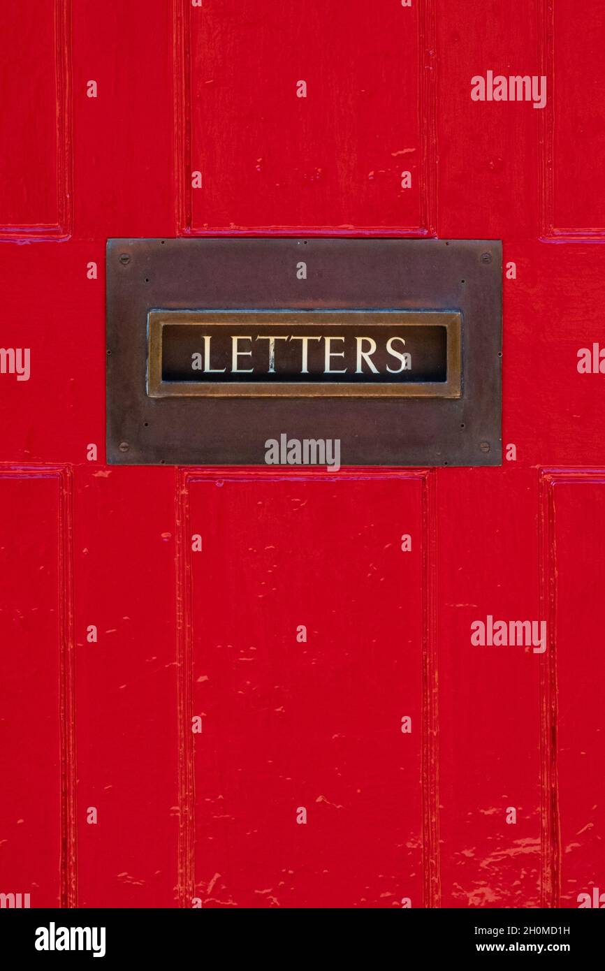 Briefkasten mit Buchstaben an der roten Tür - UK Stockfoto