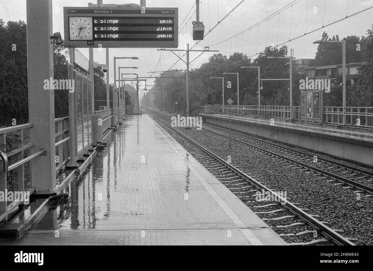 Rotterdam, Niederlande. Ein sehr regnerischer Tag auf dem Bahnsteig einer erhöhten U-Bahn-Station, an dem es sonnig und warm sein sollte. Der Klimawandel verursacht eine enorme Zunahme von Regen und Sturm an Orten, an denen sie tatsächlich sehr viel Schaden anrichten können, z. B. an der Infrastruktur. Sammlung: gkf-analoog Stockfoto