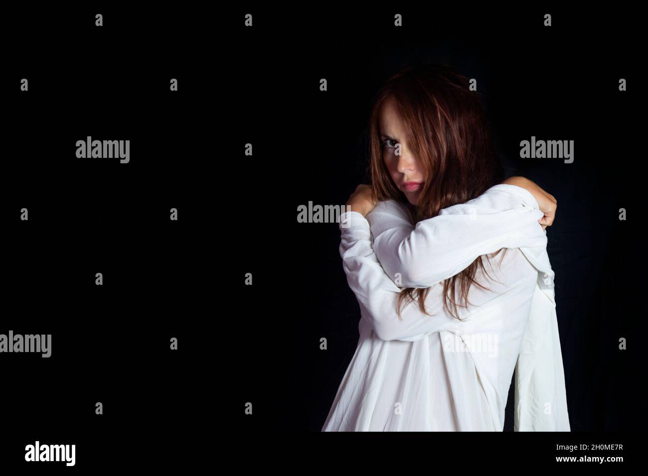 Konzept der psychischen Probleme und der psychischen Gesundheit. Porträt einer Frau in einer weißen Zwangsjacke mit einem verrückten traurigen Look Stockfoto