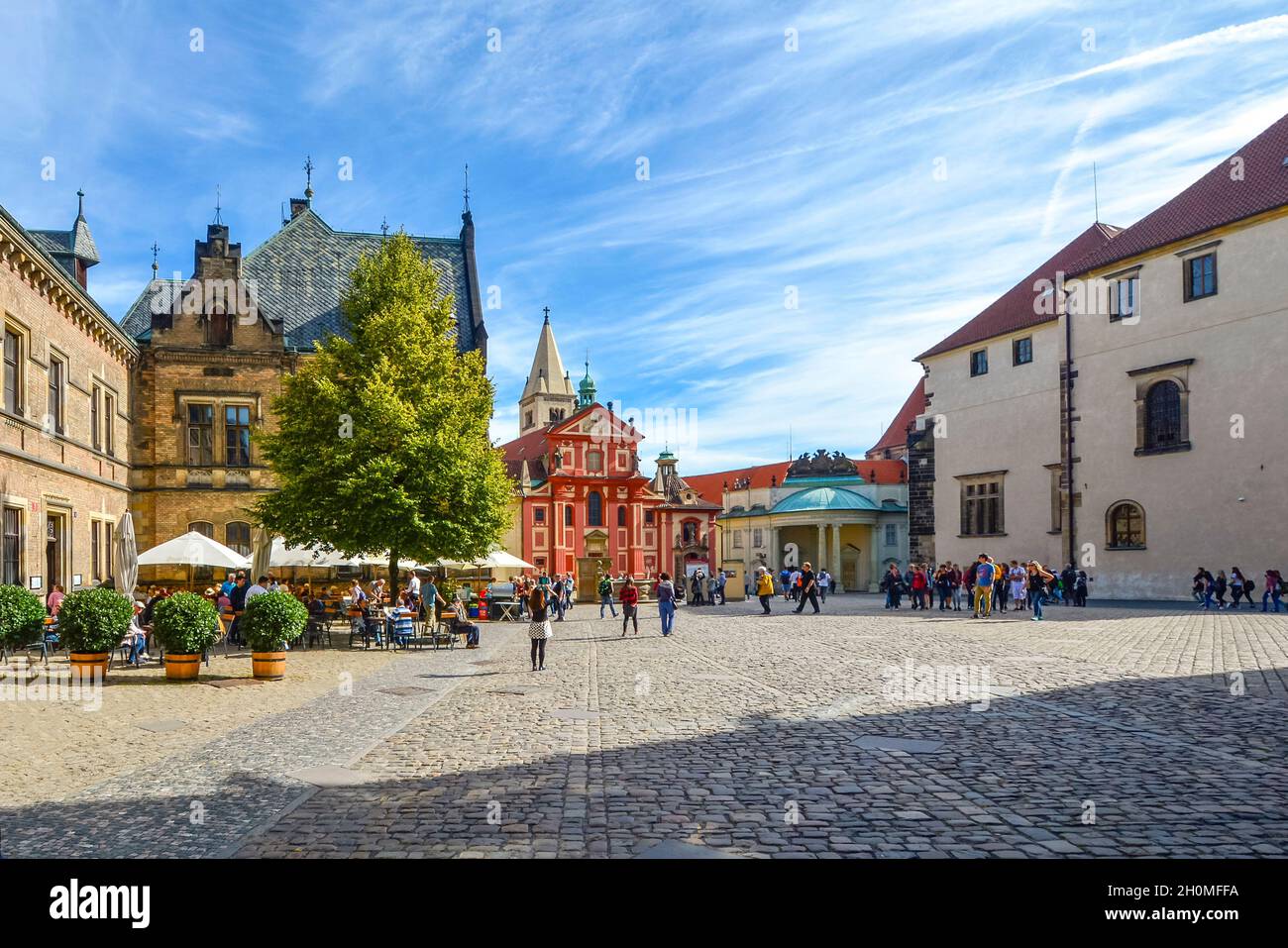 Das Innere und der Innenhof des Schlosskomplexes mit einem Café im Freien, Touristen und der St.-Georgs-Basilika in Prag, Tschechien. Stockfoto