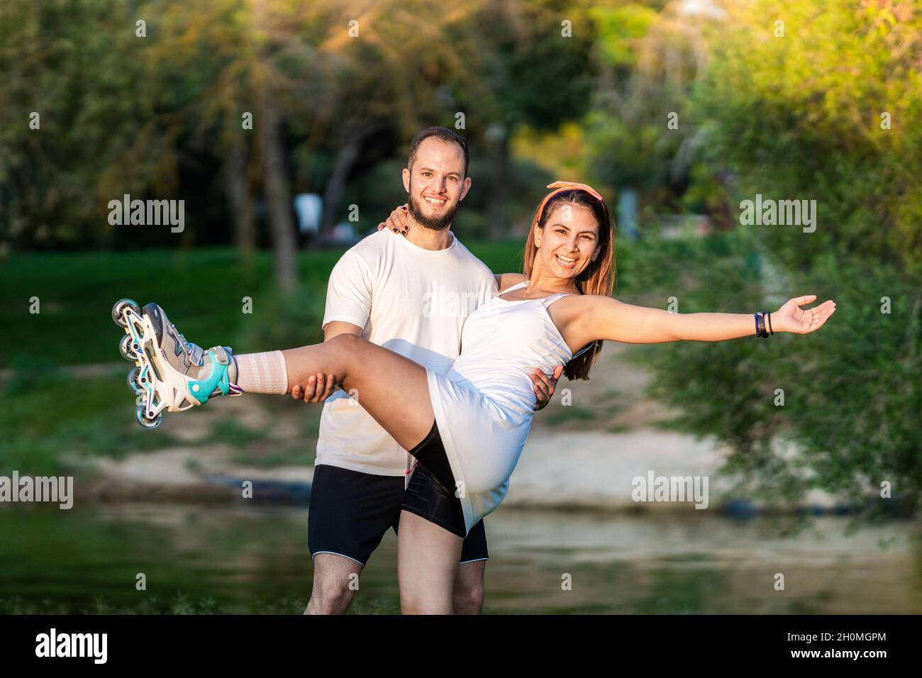 Zwei Personen posieren im Gleichgewicht mit Inline-Skates in einem Park Stockfoto
