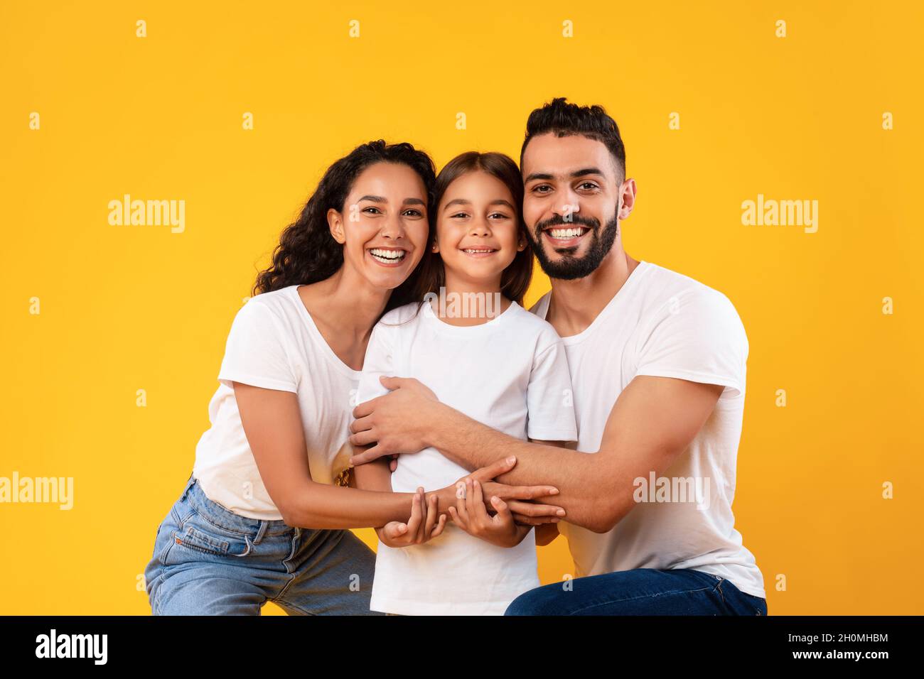 Glückliche Eltern Aus Dem Nahen Osten Umarmen Ihre Tochter Auf Gelbem Hintergrund Stockfoto