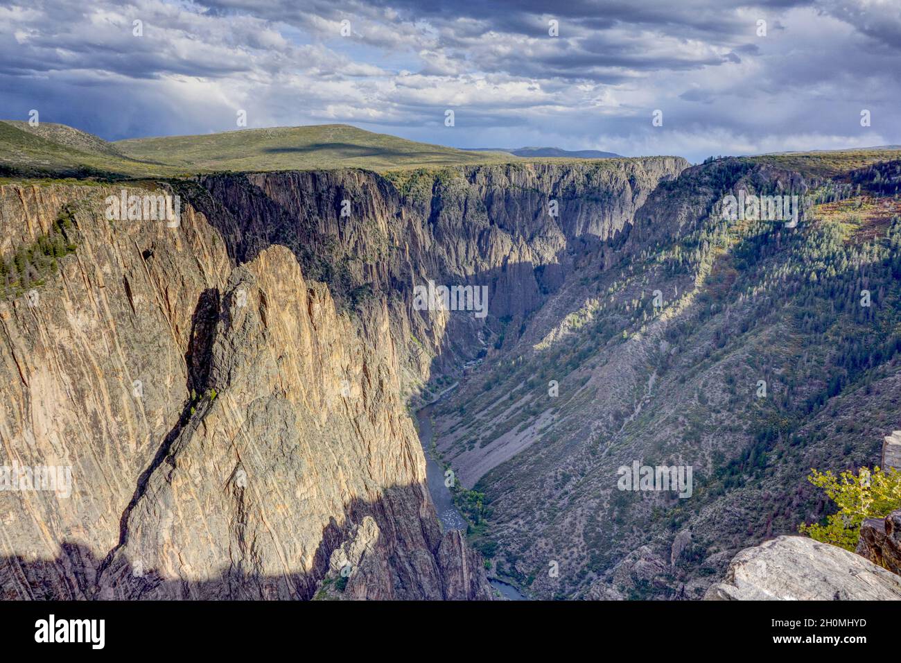 Black Canyon des Gunnison National Park mit dem Gunnison River, der am Ende des Canyons sichtbar ist. Sturmwolken sammeln sich. Stockfoto