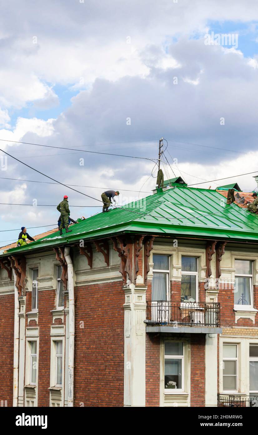 Arbeiter auf dem Dach wechseln das Dach, das die Bettwäsche eines historischen modernistischen Gebäudes bedeckt. Wartungs- und Umbauarbeiten in St. Petersburg Russland Stockfoto