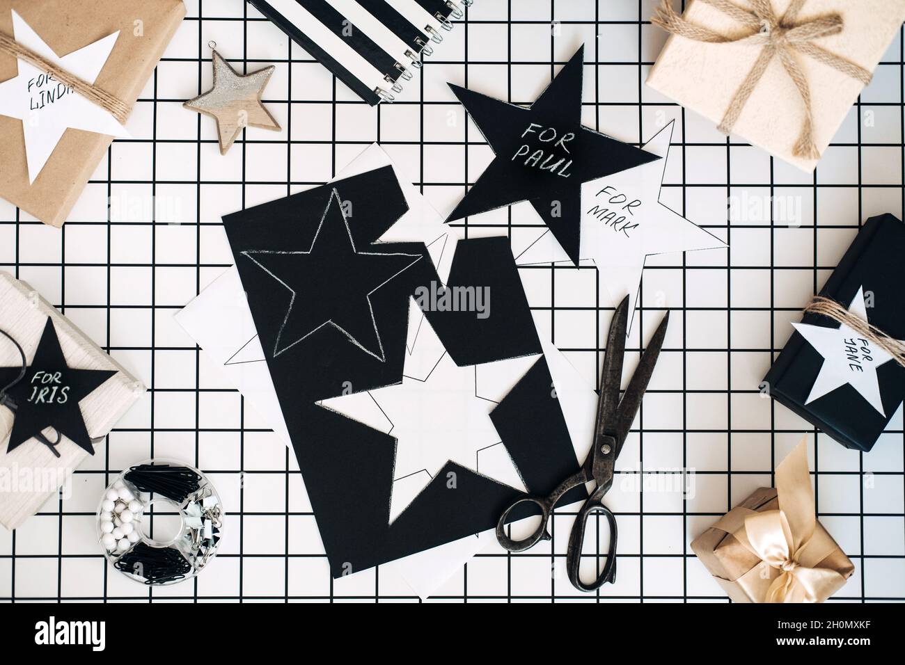 Personalisierte Geschenke. Modernes Schwarz-Weiß-Flachlappen mit Geschenkverpackung für Weihnachten. Scheren, eingewickelte Bastelkisten mit Namen und Verpackung Stockfoto