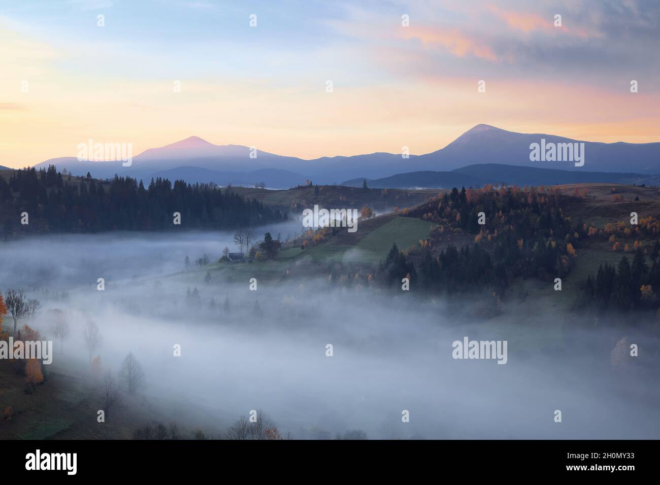 Herbstlandschaft. Landschaft mit den Bergen, Sonnenaufgang, blauer Himmel mit orangefarbenen Wolken. Landschaft, Felder, Wälder im Morgennebel. Touristenr Stockfoto