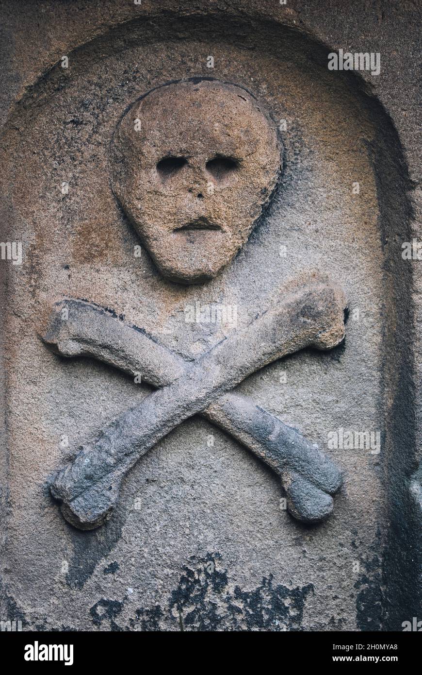 Schädel und Kreuzknochen auf dem Grab im St. Lawrence Kirchhof des Pestdorfes Eyam, Peak District, Derbyshire, England Stockfoto