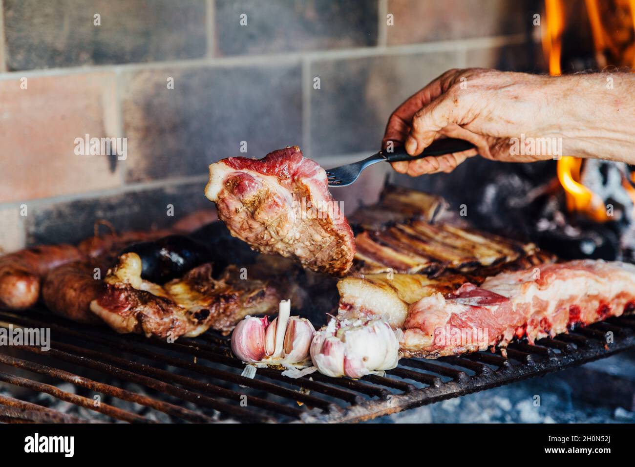 Argentinisches Fleisch auf dem Grill braten. Mann, der ein traditionelles Barbecue namens Asado in Argentinien macht. Stockfoto
