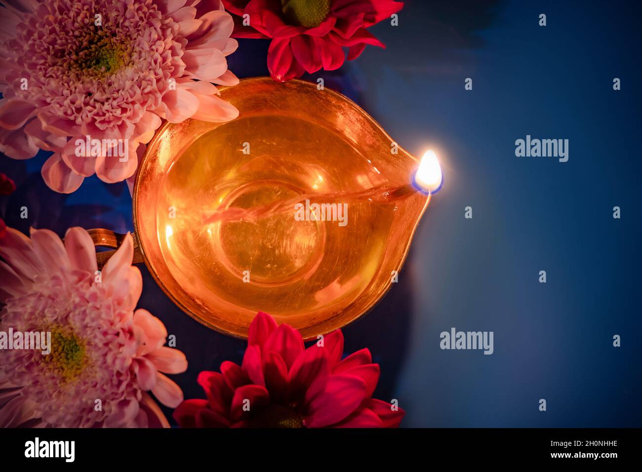 Feier des indischen Festival des Lichts Diwali. Nahaufnahme von traditionellen Diya-Öllampen und Blumen auf blauem Hintergrund. Stockfoto