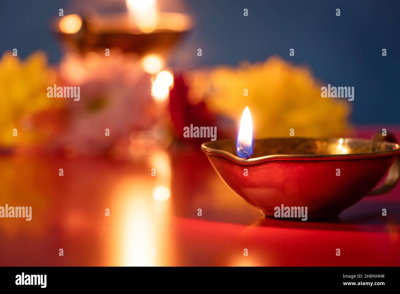 Frohes Diwali. Brennende Diya-Öllampen und Blumen auf blauem Hintergrund. Traditionelles indisches Festival des Lichts. Wir feiern religiöse Feiertage. Stockfoto