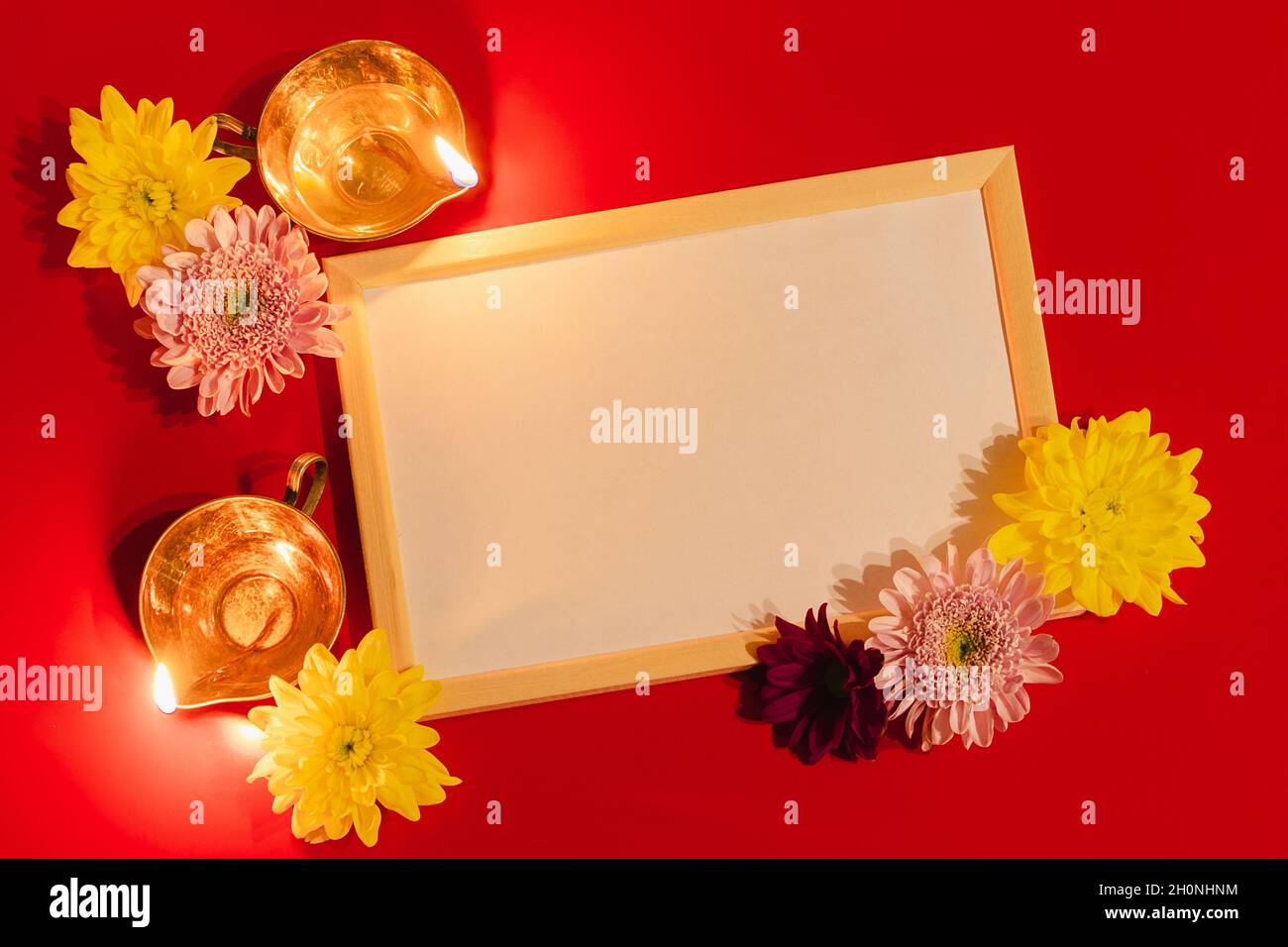 Frohes Diwali. Diya Öllampe und Blumen auf rotem Hintergrund. Feier des traditionellen indischen Festivals des Lichts. Leerer Rahmen für Text. Stockfoto