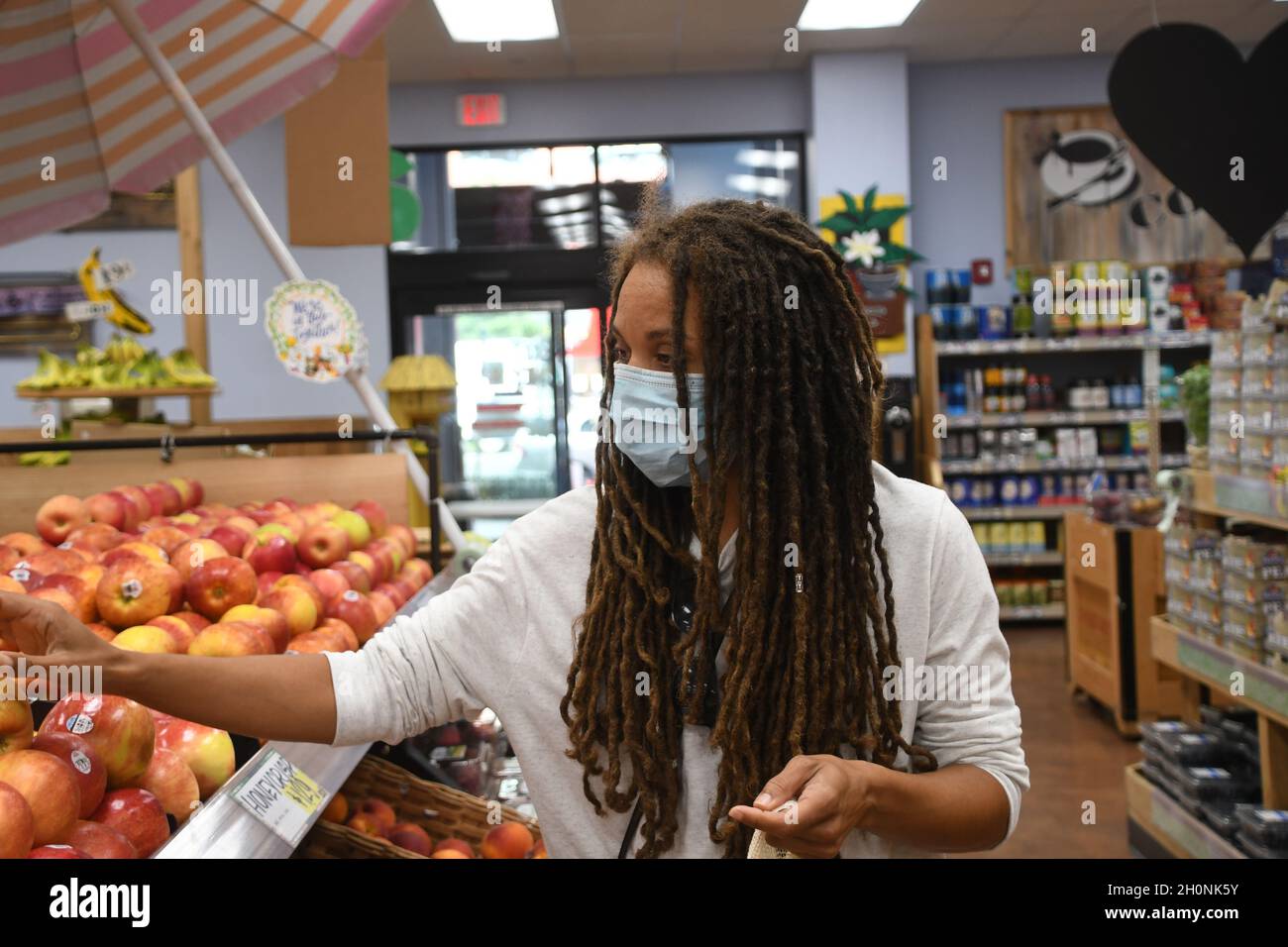 Frau kauft in einem Lebensmittelgeschäft während einer globalen Covid-19-Pandemie in einer Maske ein. Stockfoto