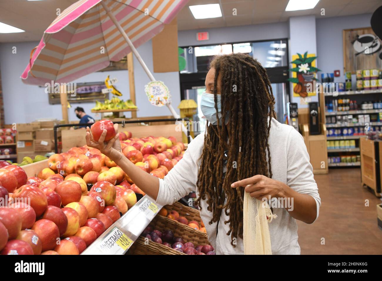 Frau kauft in einem Lebensmittelgeschäft während einer globalen Covid-19-Pandemie in einer Maske ein. Stockfoto