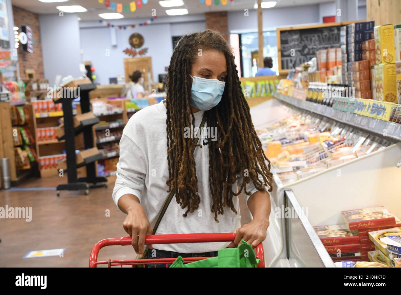 Frau kauft in einem Lebensmittelgeschäft während einer globalen Covid-19-Pandemie in einer Maske ein. Stockfoto