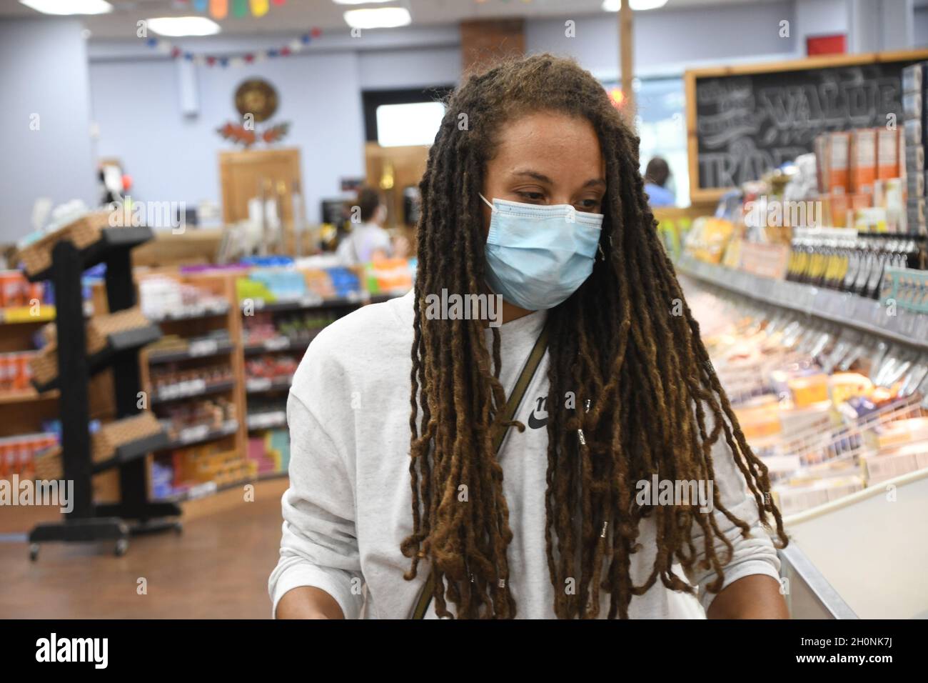 Frau kauft in einem Lebensmittelgeschäft während einer globalen Covid-19-Pandemie in einer Maske ein. Stockfoto