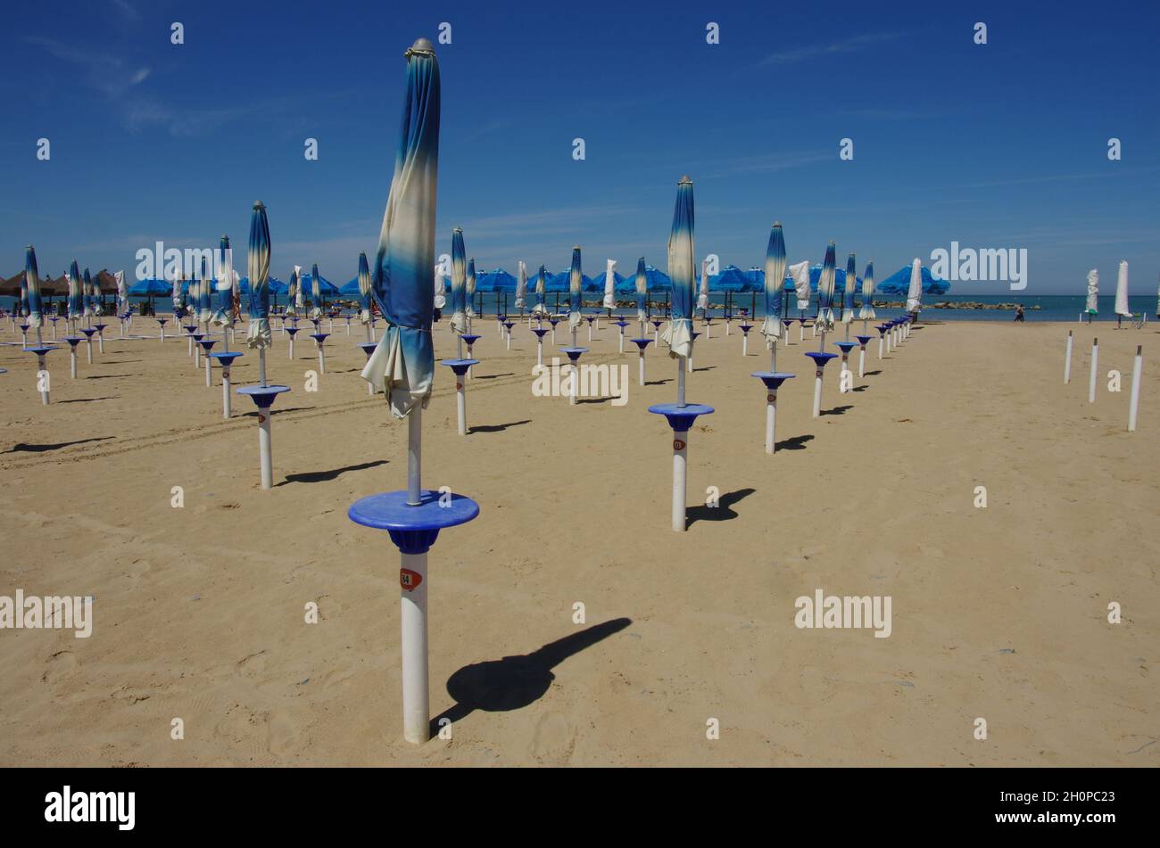 Strand mit weißen und blauen geschlossenen Sonnenschirmen Stockfoto