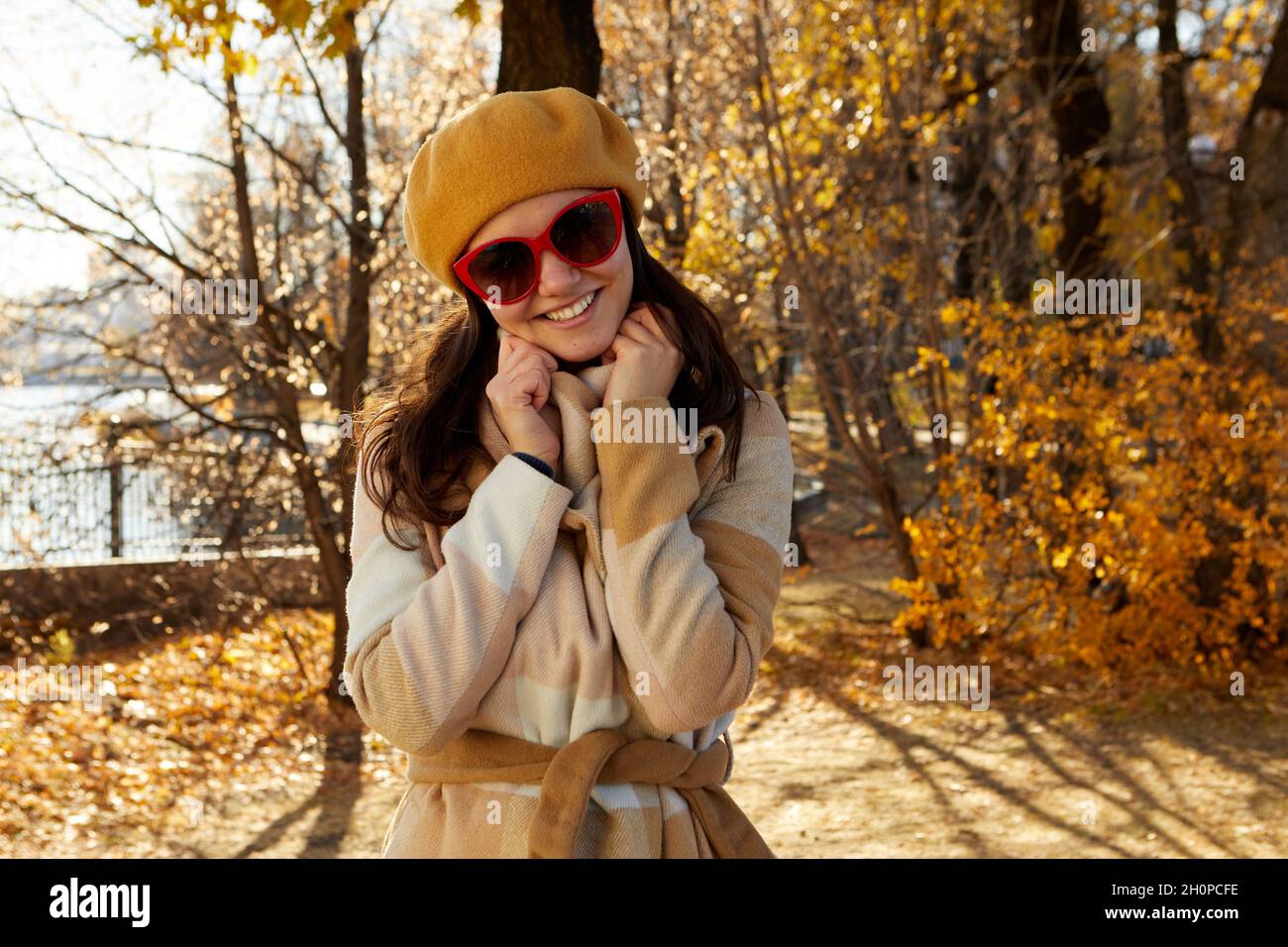 Saisonale Herbstmode. Moderne junge Frau in modisch warmen Kleidern, die im Herbstpark posiert Stockfoto