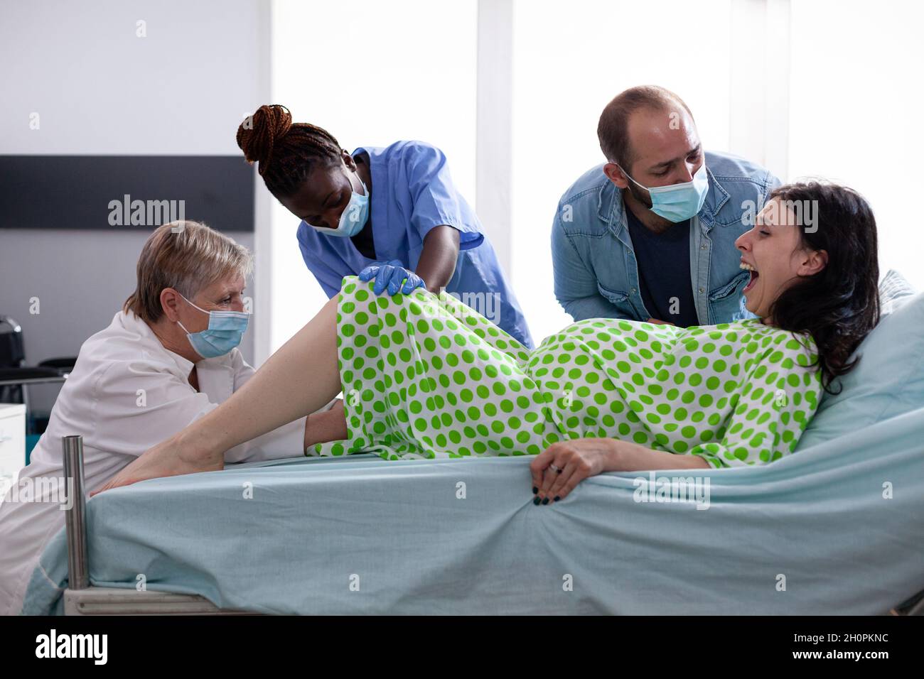 Multiethnisches medizinisches Team, das Kind und Frau in das Bett der  Krankenstation schiebt. Erwachsene mit schmerzhaften Kontraktionen, die ein  Baby gebären, während Arzt, Krankenschwester und Ehemann assistieren  Stockfotografie - Alamy