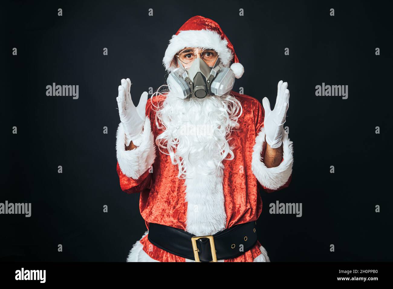 Mann, der als Weihnachtsmann gekleidet ist und eine Kohlefilter-Maske trägt, um einen Virus zu vermeiden, auf schwarzem Hintergrund. Weihnachtskonzept, Weihnachtsmann, Geschenke, Celebra Stockfoto