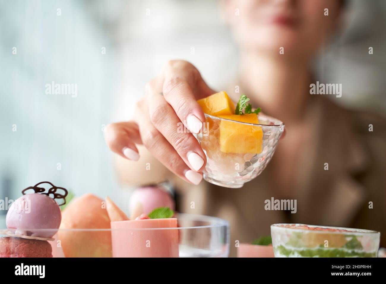 Nahaufnahme der Hände einer asiatischen Frau, die am Esstisch im Restaurant ein Dessert abholt Stockfoto
