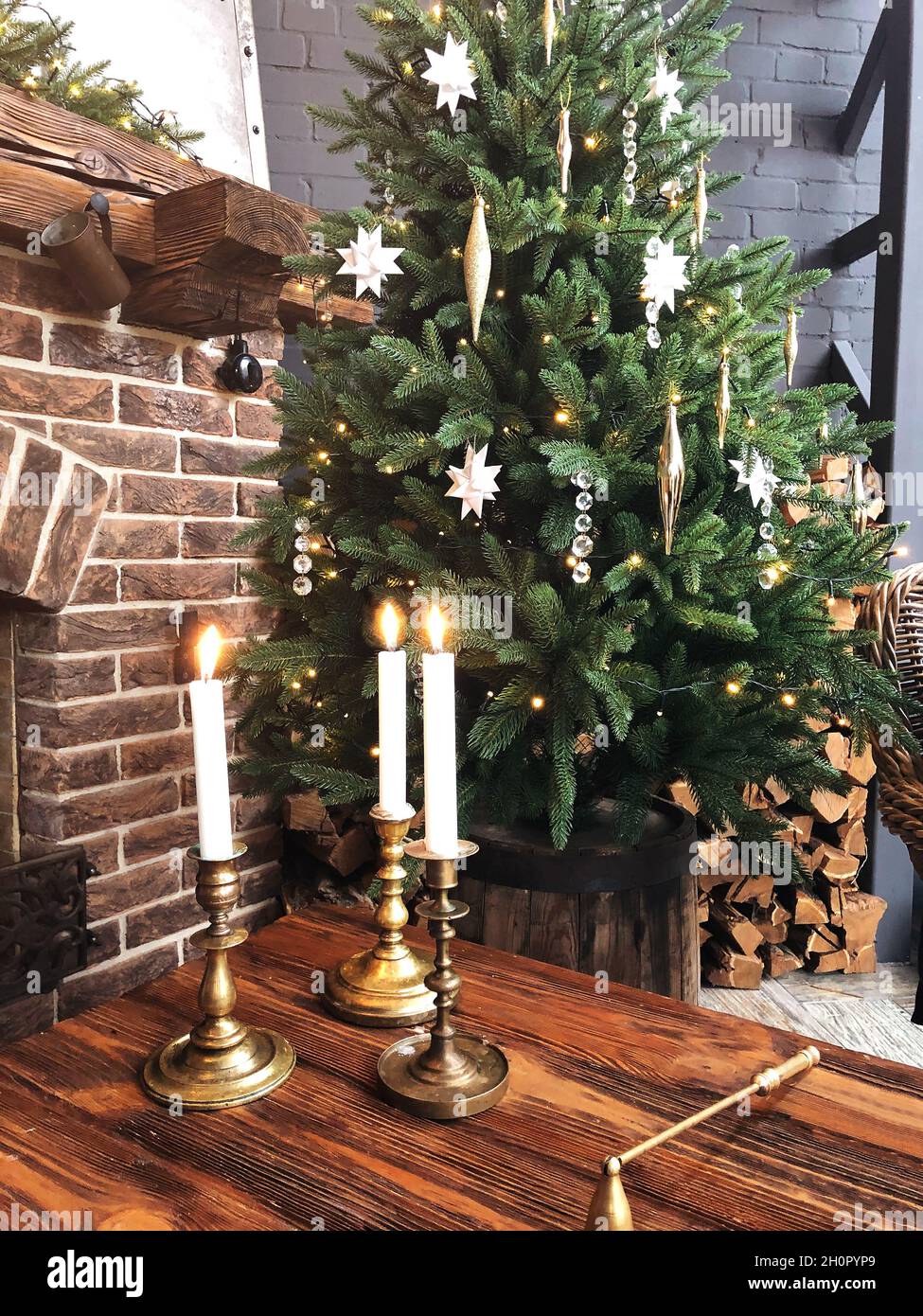 Brennende Kerzen in Vintage-Metall-Kerzenständer auf Holztisch in der Nähe für weihnachtsbaum in gemütlichen Raum mit Kamin dekoriert, warme Weihnachten backgroun Stockfoto