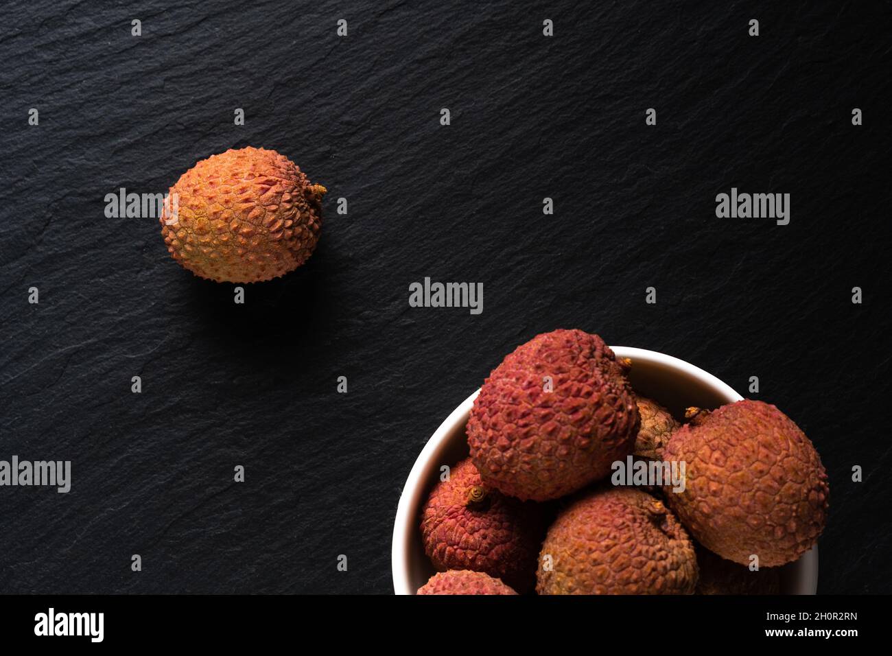 Litchi-Früchte auf schwarzem Hintergrund. Minimaler Obstsommer-Konzept. Stockfoto