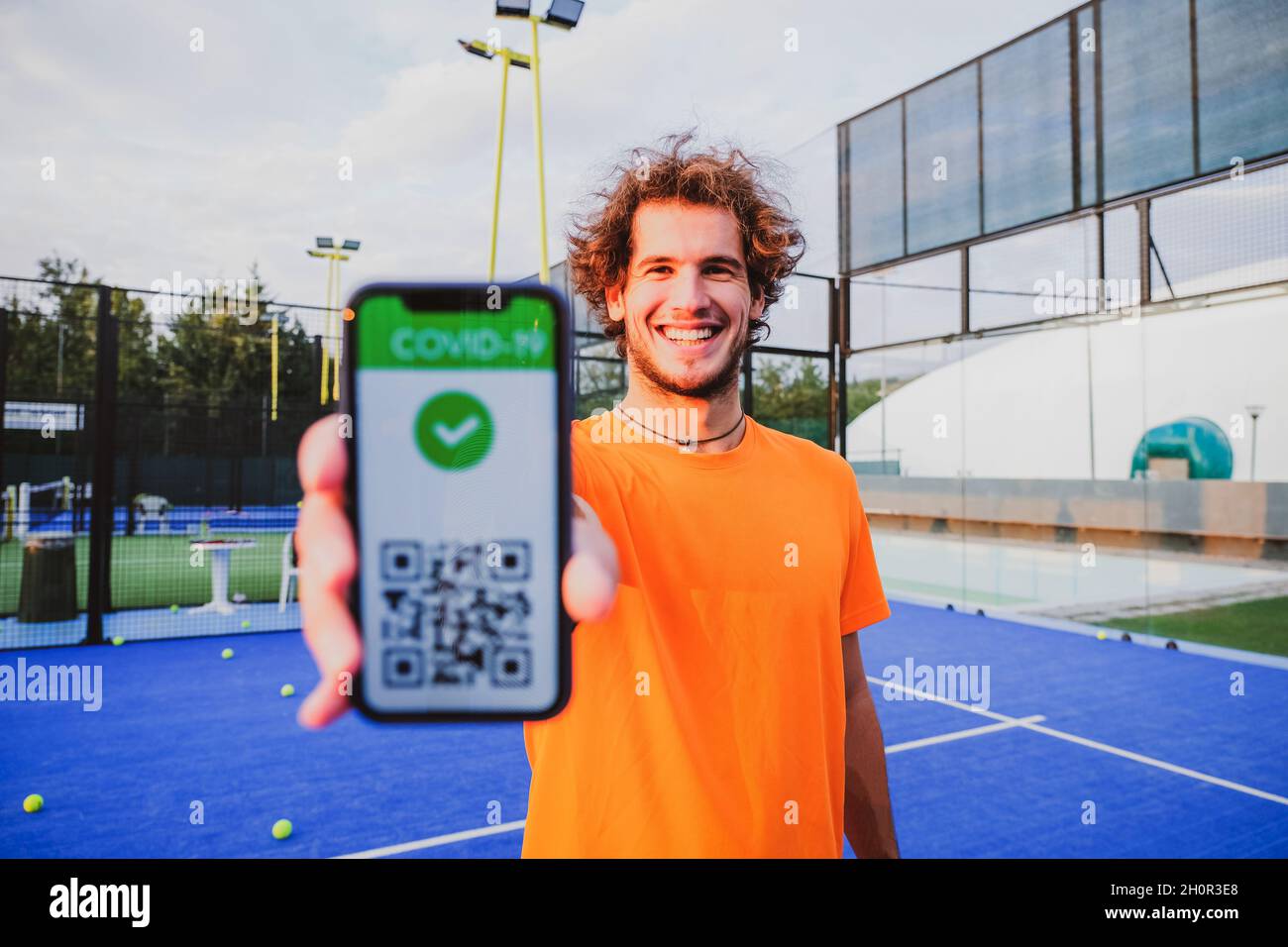 Junger Mann zeigt Impfpass covid-19 mit App auf Smartphone erster Sport, Coronavirus-Konzept Stockfoto