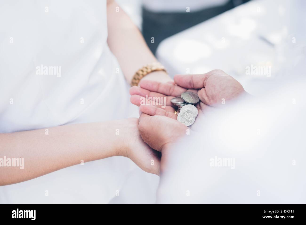 Während der Hochzeitszeremonie können Sie Palmen mit den Unity Coins, bekannt als Las Arras oder Arrhae, über den Handflächen der Braut halten. Selektiver Fokus. Speicherplatz kopieren. Stockfoto