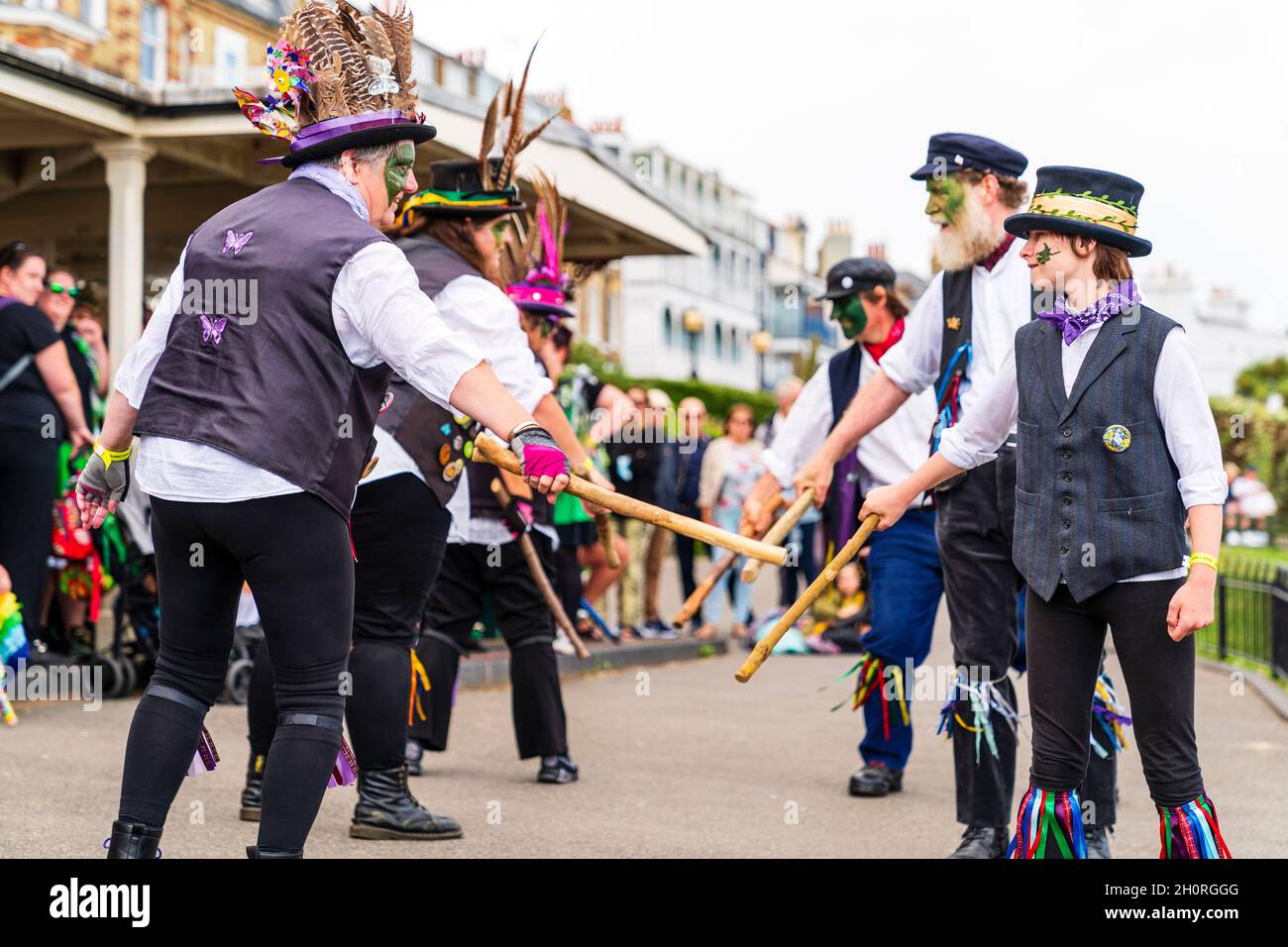 Dead Horse morris tanzt an der Strandpromenade während des Broadstairs Folk Week Festivals. Zwei Reihen von Tänzern, die einander gegenüberstehen und Holzstangen halten. Stockfoto