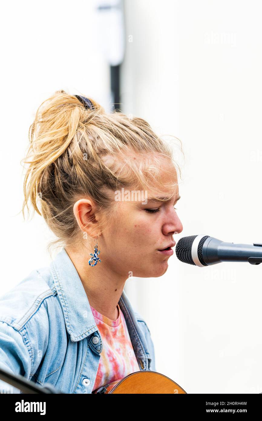 Nahaufnahme des Gesichts von Mimi O'Halloran, einer jungen Singer-Songwriterin, die bei einem Open-Air-Konzert bei einer Veranstaltung in ein Mikophon singt. Stockfoto