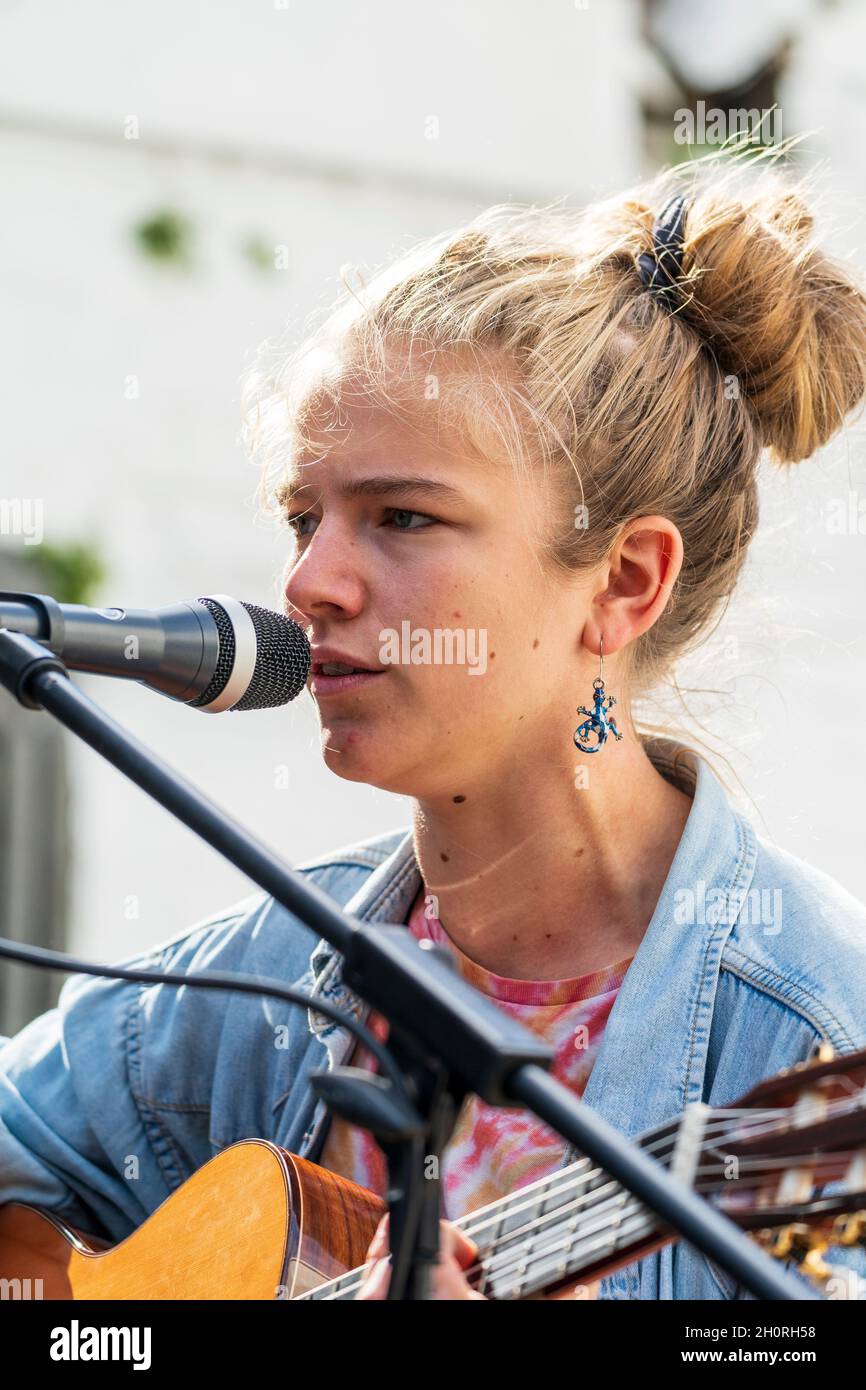 Nahaufnahme des Gesichts von Mimi O'Halloran, einer jungen Singer-Songwriterin, die bei einem Open-Air-Konzert bei einer Veranstaltung in ein Mikophon singt. Stockfoto