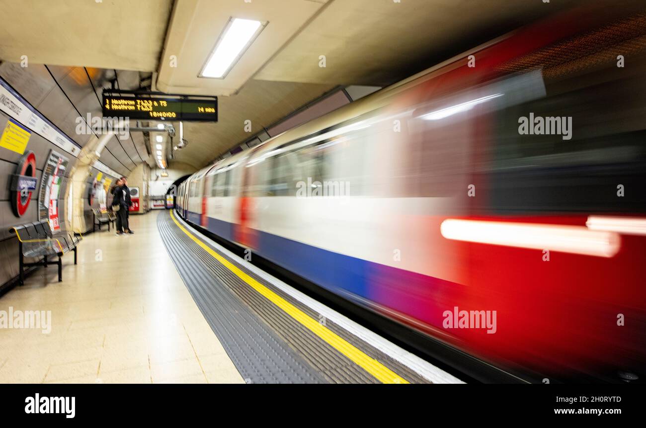 Die Londoner U-Bahn (The Tube) fährt mit hoher Geschwindigkeit am Bahnhof Knightsbridge in Richtung Heathrow; verschwimmt von langer Belichtung und langsamer Verschlusszeit Stockfoto