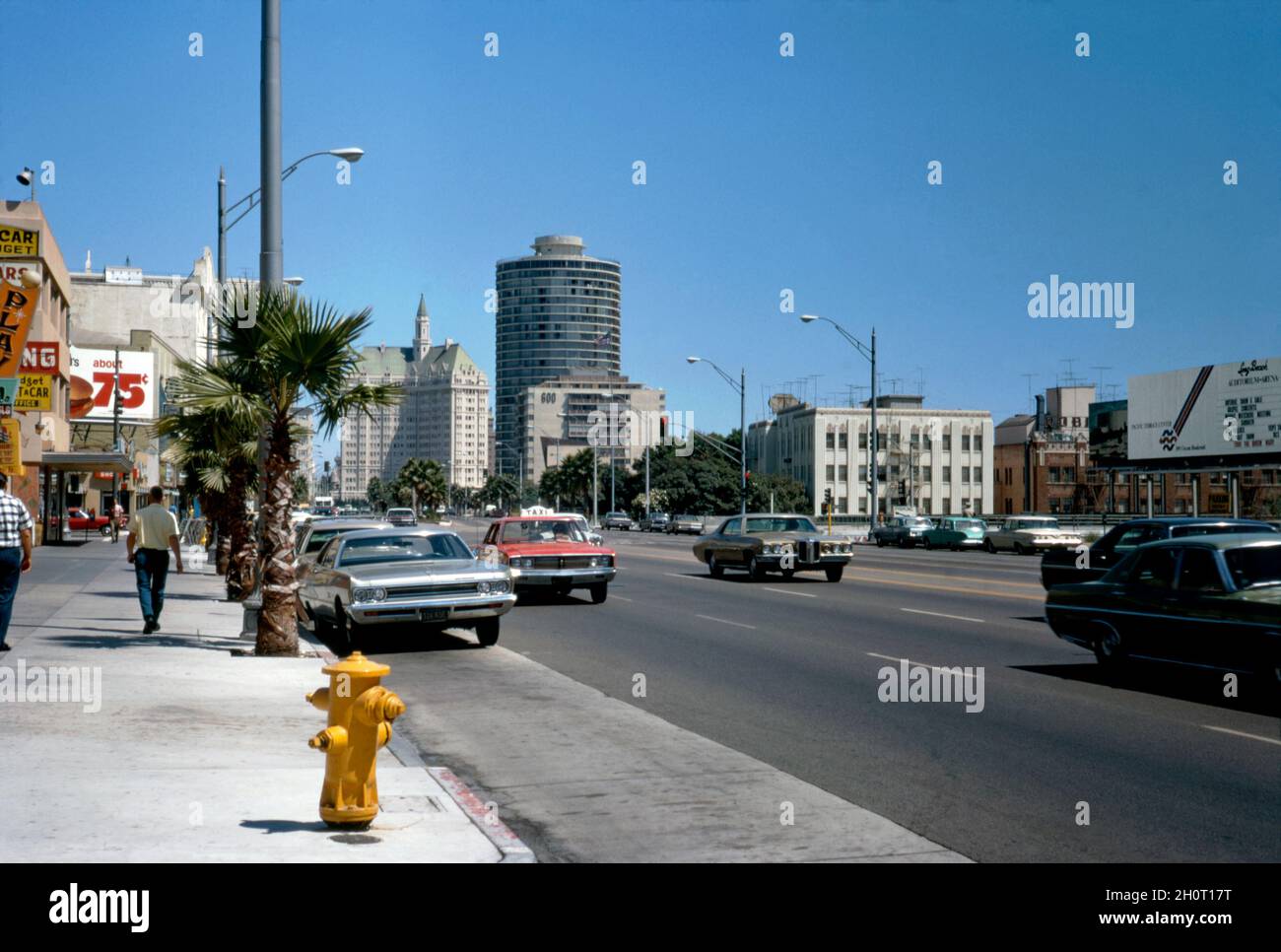 Ein Blick auf einen belebten East Ocean Boulevard, Long Beach, Kalifornien, USA im Jahr 1972. Die Stadt liegt im Stadtgebiet von Los Angeles. Dies ist eine der Hauptstraßen in der Innenstadt. Das runde Gebäude ist der International Tower. 1966 als 32-stöckiger runder Apartmentkomplex erbaut. In der Ferne befindet sich die Villa Riviera, die 1929 erbaut wurde. Das elegante, 16-stöckige Gebäude im Château-Stil wird derzeit als Wohnanlagen genutzt. Dieses Bild stammt von einem alten amerikanischen Amateur Kodak Farbtransparenz – einem Vintage-Foto aus den 1970er Jahren. Stockfoto