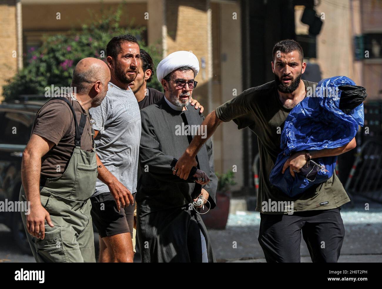 Beirut, Libanon. Oktober 2021. Ein libanesischer muslimischer schiitischer Geistlicher wird bei Zusammenstößen im Gebiet von Tayouneh evakuiert, nachdem bei einem Protest von Anhängern der schiitischen Hisbollah-Bewegung gegen den Richter, der die Hafenexplosion der Stadt untersucht, in der Nähe der ehemaligen Bürgerkriegsfront zwischen muslimischen schiitischen und christlichen Gebieten Schüsse ausgebrochen sind. Mindestens sechs Menschen wurden in Beirut getötet und 30 verletzt, als bei einem Protest gegen den Richter, der die Explosion im Hafen der Stadt im vergangenen Jahr untersucht, ein Schießfeuer ausbrach, sagte das libanesische Rote Kreuz. Quelle: Marwan Naamani/dpa/Alamy Live News Stockfoto