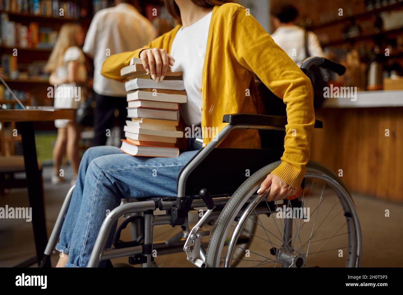 Eine behinderte Studentin hält einen Stapel Bücher Stockfoto