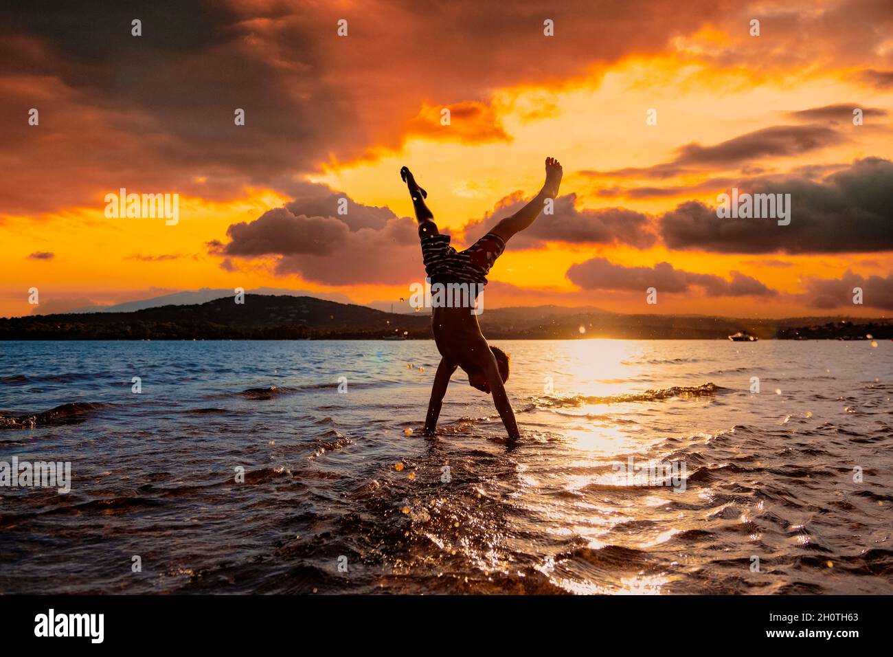 Kind spielt im Meer bei Sonnenuntergang. Stockfoto