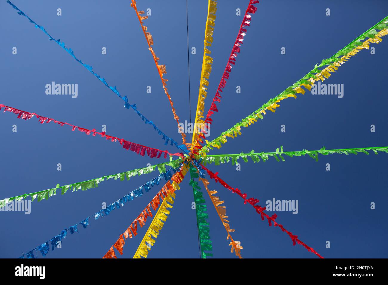 Typische Girlande beliebter Feste, die an den Wänden hängen und einen Stern bilden, von unten gesehen mit dem Himmel im Hintergrund. Stockfoto