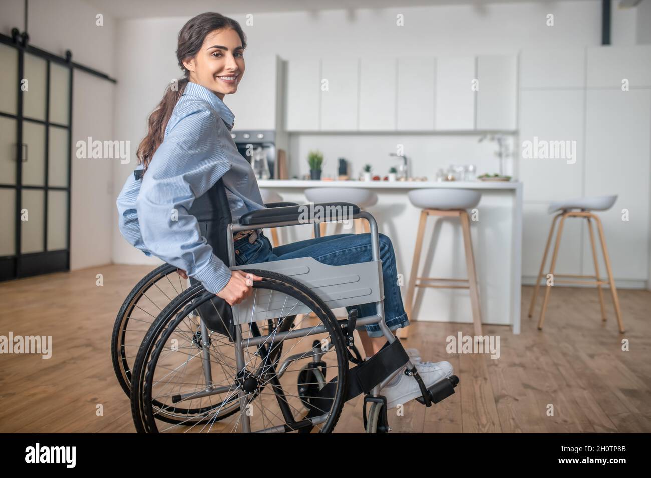 Eine lächelnde junge Frau, die in einem Rollstuhl sitzt Stockfoto