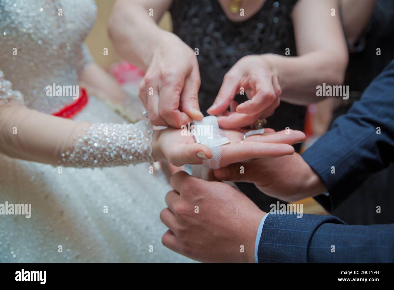 Die Braut legt ihr das Taschentuch in die Hände. Die Hand der Braut ist am Bogen befestigt Stockfoto