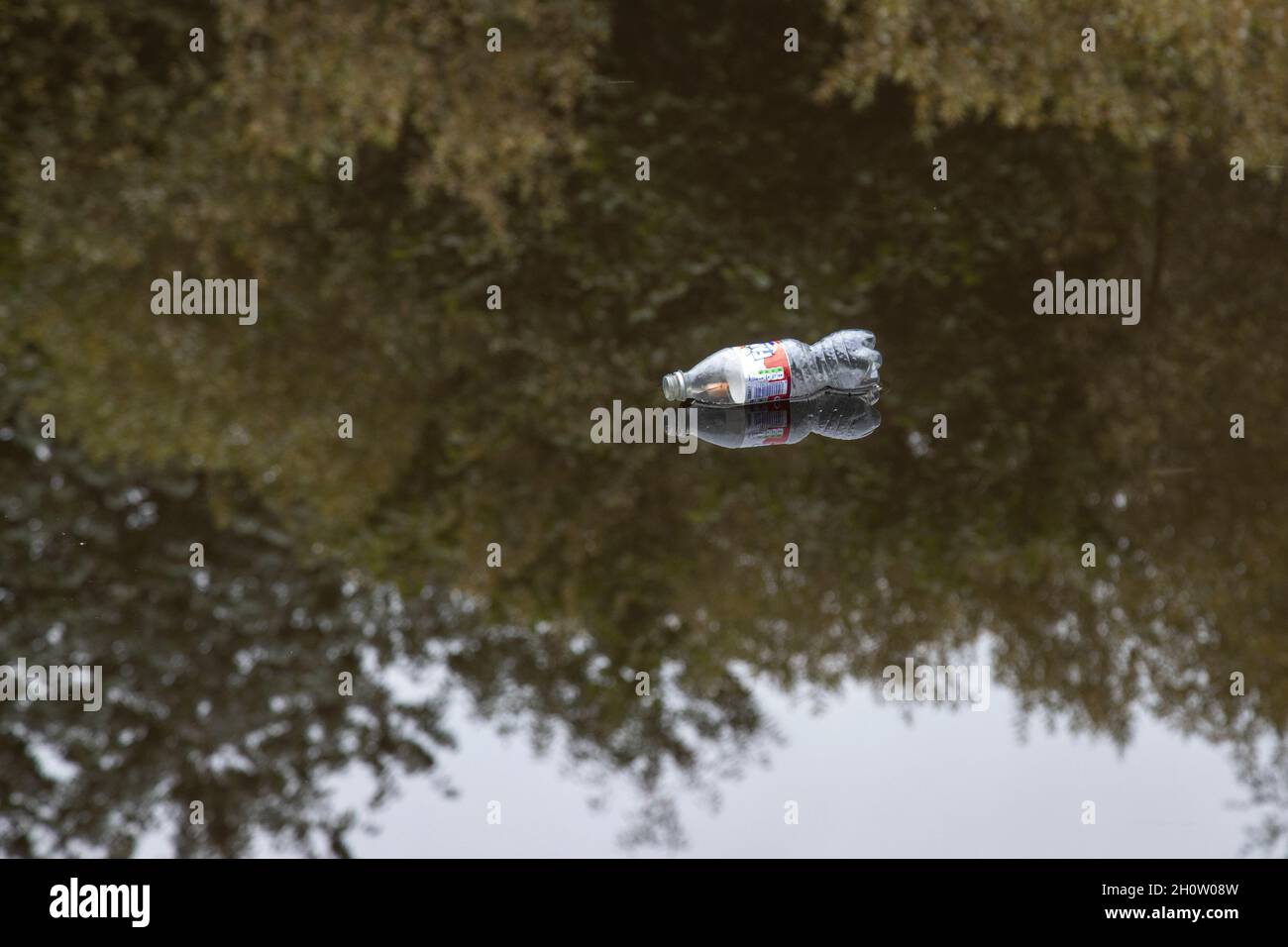 Weggeworfene alkoholfreie Getränkeflaschen aus Kunststoff, die in einem Kanal schwimmen und die Plastikverschmutzung erhöhen, die auf dem Planeten dringende Umweltprobleme verursacht Stockfoto