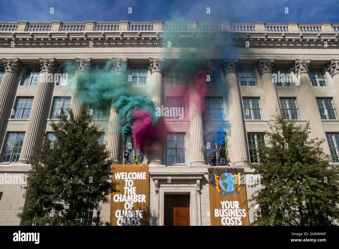 Mitglieder der Extinction Rebellion brennen während eines Klimaproteste in Washington, DC, USA, am 14. Oktober 2021 vor der US-Handelskammer Fackeln. Die Aktionsgruppe demonstriert gegen die aktuelle Klimapolitik von Regierungen auf der ganzen Welt. Stockfoto