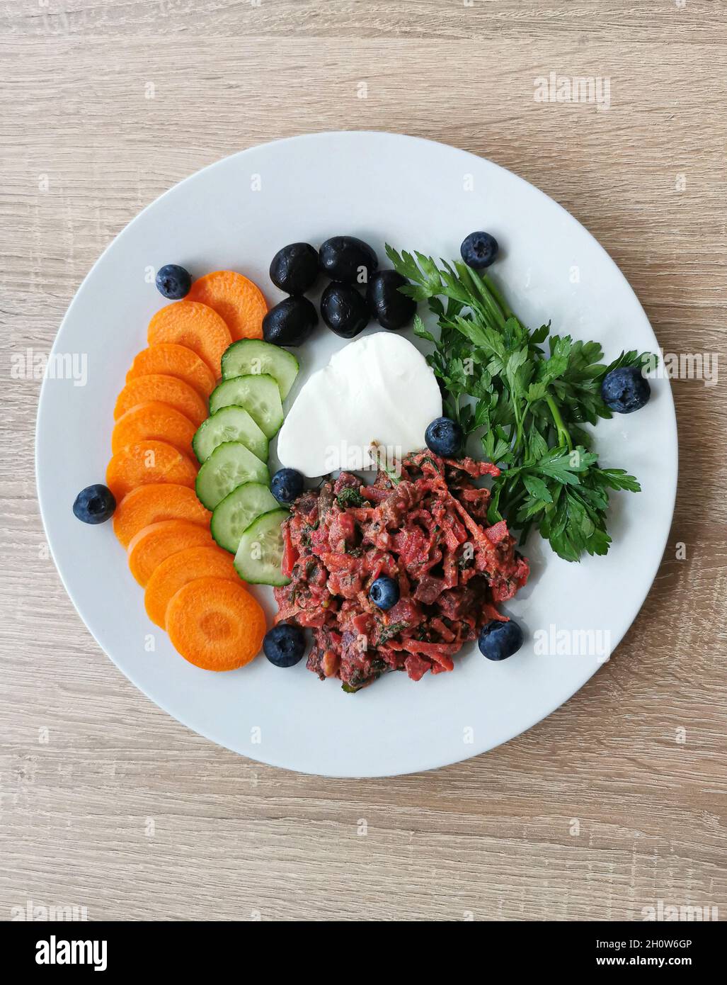 Stück Mokarella-Käse, schwarze Oliven, verschiedenes buntes Gemüse und Heidelbeeren Stockfoto