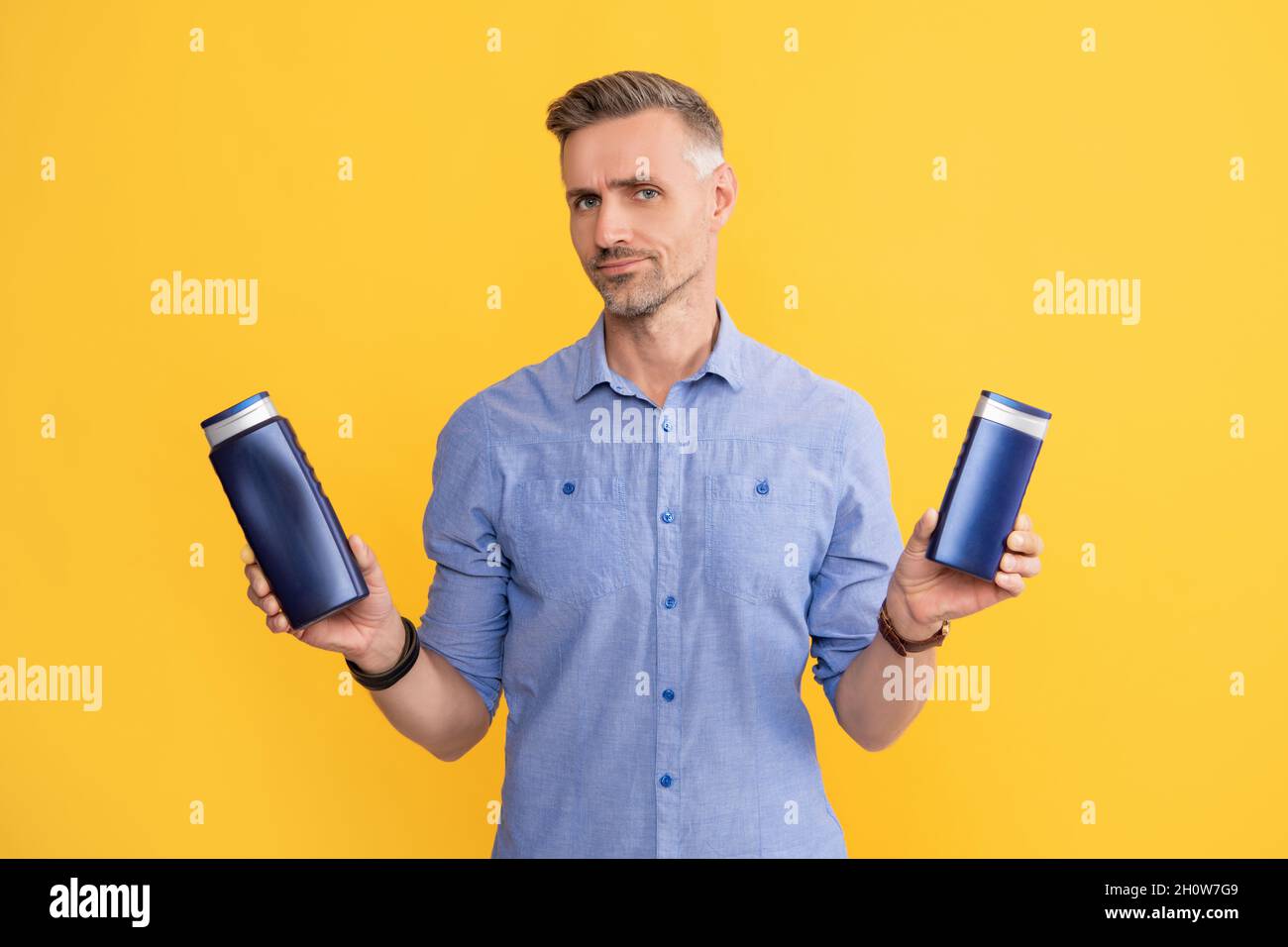 Guy wählen Shampoo-Flasche oder Haarspülung. Tägliche Gewohnheiten und persönliche Pflege. Stockfoto
