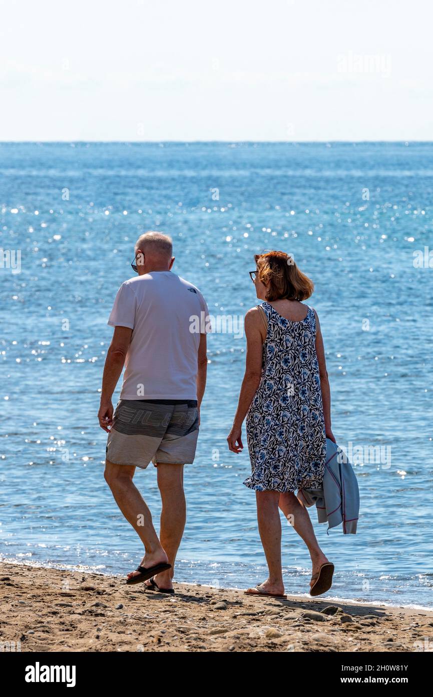 Ehepaar mittleren Alters oder Rentner, die am Strand am Ufer entlang auf der griechischen ionischen Insel Zante oder zakynthos Urlaub machen. Stockfoto
