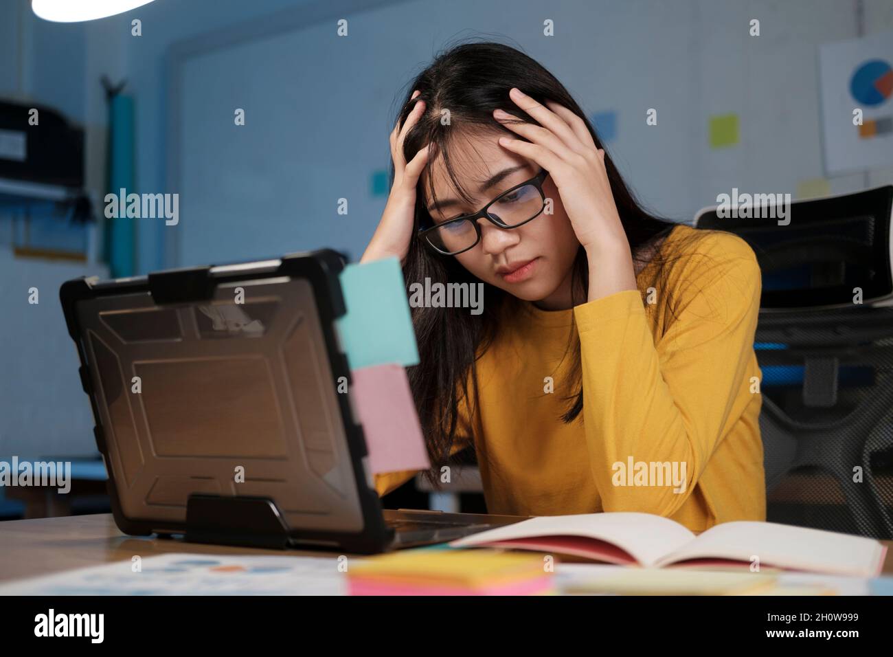 Gestresste, erschöpfte Frau, die am Schreibtisch sitzt und Überstunden macht, ist mit Arbeit überladen. Stockfoto