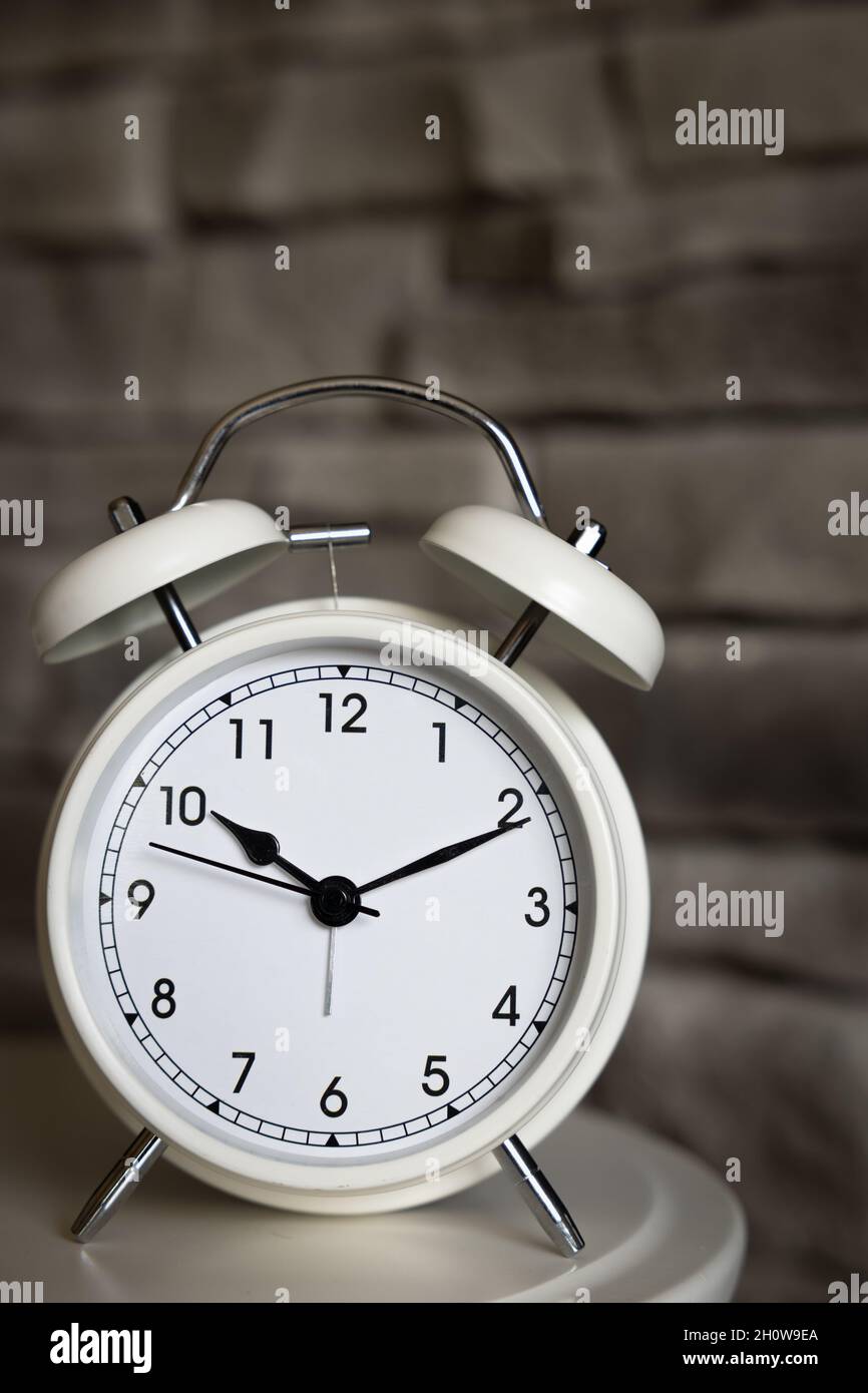 Kleiner weißer Retro-Wecker mit grauem Steinhintergrund und Kopierraum Stockfoto