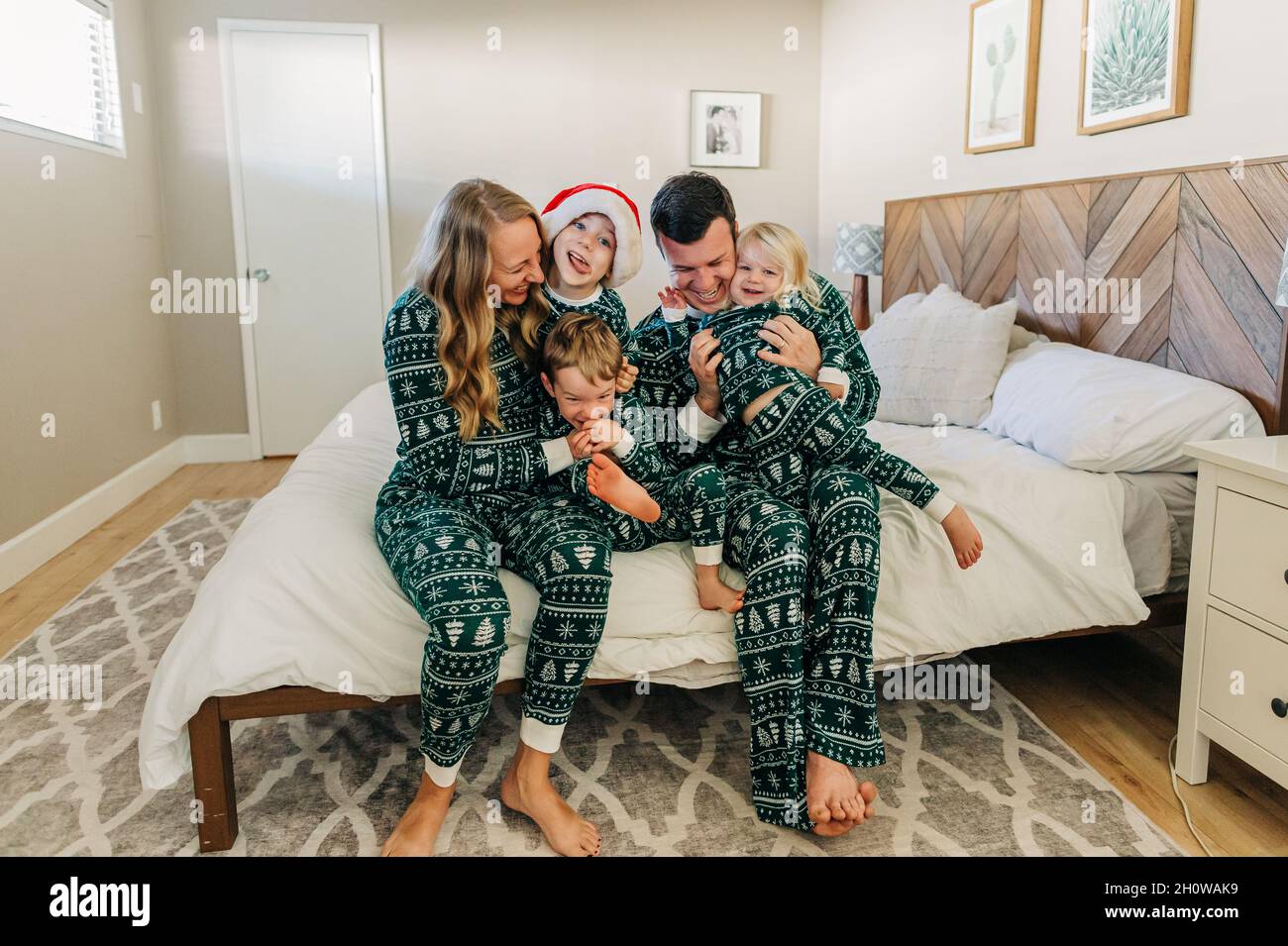 Kaukasische Familie im weihnachts-Pyjama kuschelt sich auf das Bett in Phoenix-Haus Stockfoto