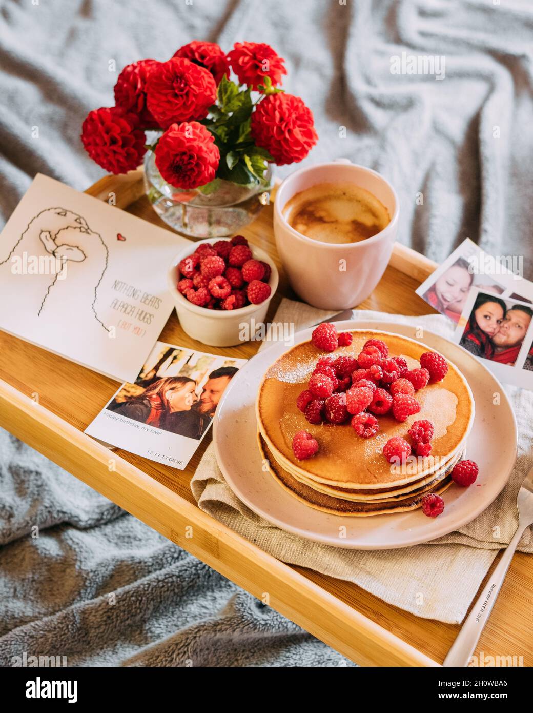 Frühstück im Bett: Pfannkuchen, Blumen und Fotos von Paaren Stockfoto