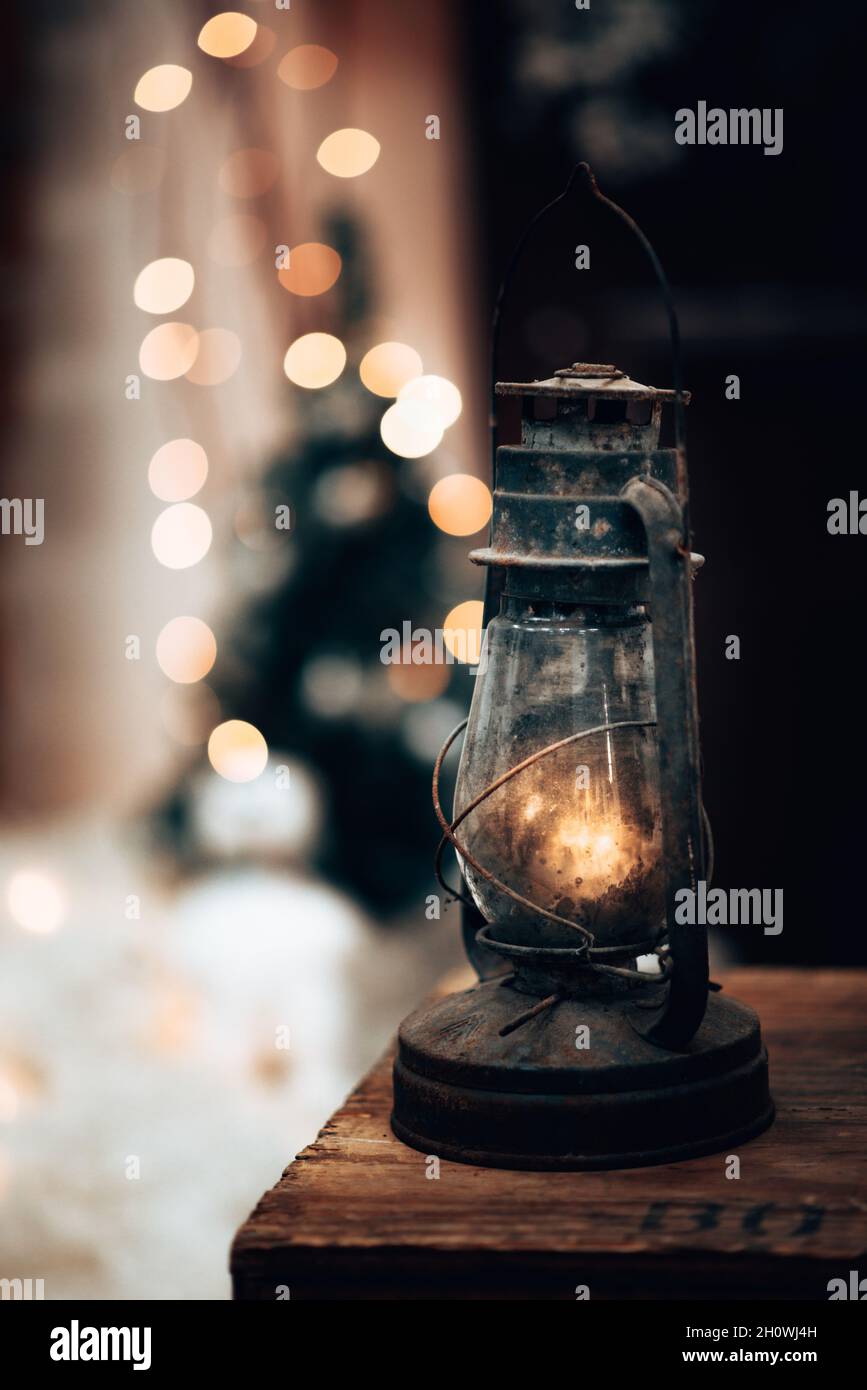 Vertikale Nahaufnahme einer Vintage-Lampe auf einem Tisch mit Bokeh-Lichtern im Hintergrund Stockfoto